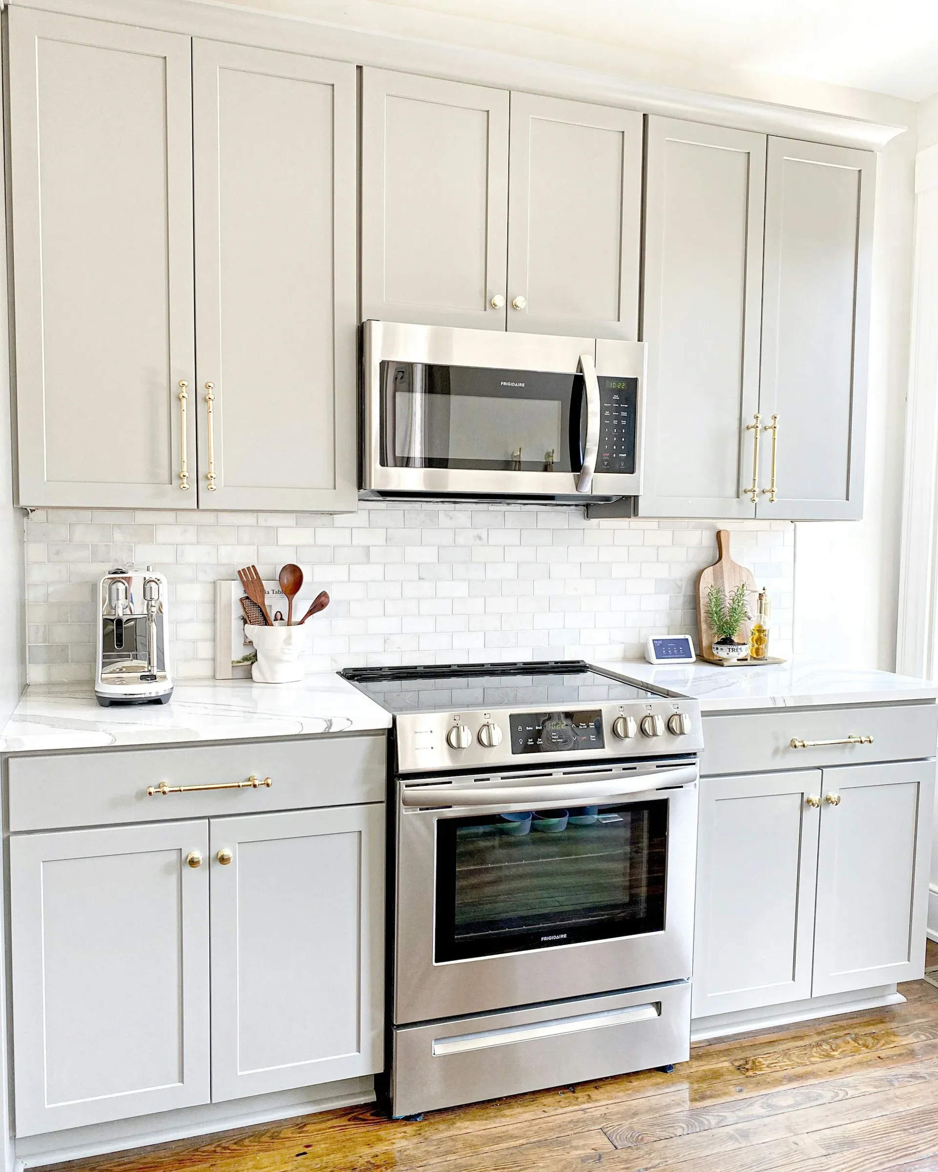 Stylish kitchen with gray cabinets, white marble countertop, stainless steel stove and microwave, and a cozy, modern ambiance.